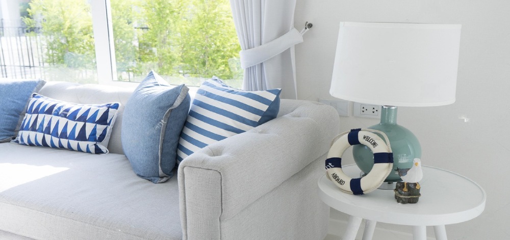 sillón blanco de espaldas a una ventana con cojines azules