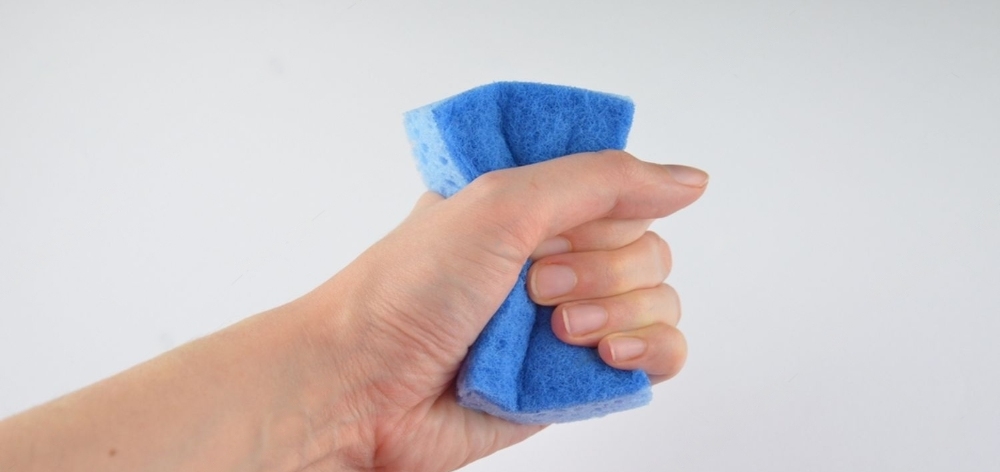 mano exprimiendo una esponja azul