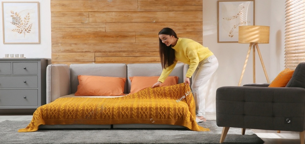mujer tendiendo su cama con cubrecama amarilla y cojines naranjas