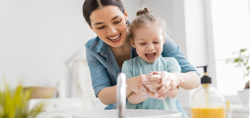 mamá lavándole las manos a su hija en el baño